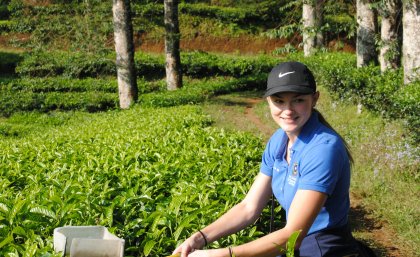 Jessica Harper sitting amidst green-coloured crops 